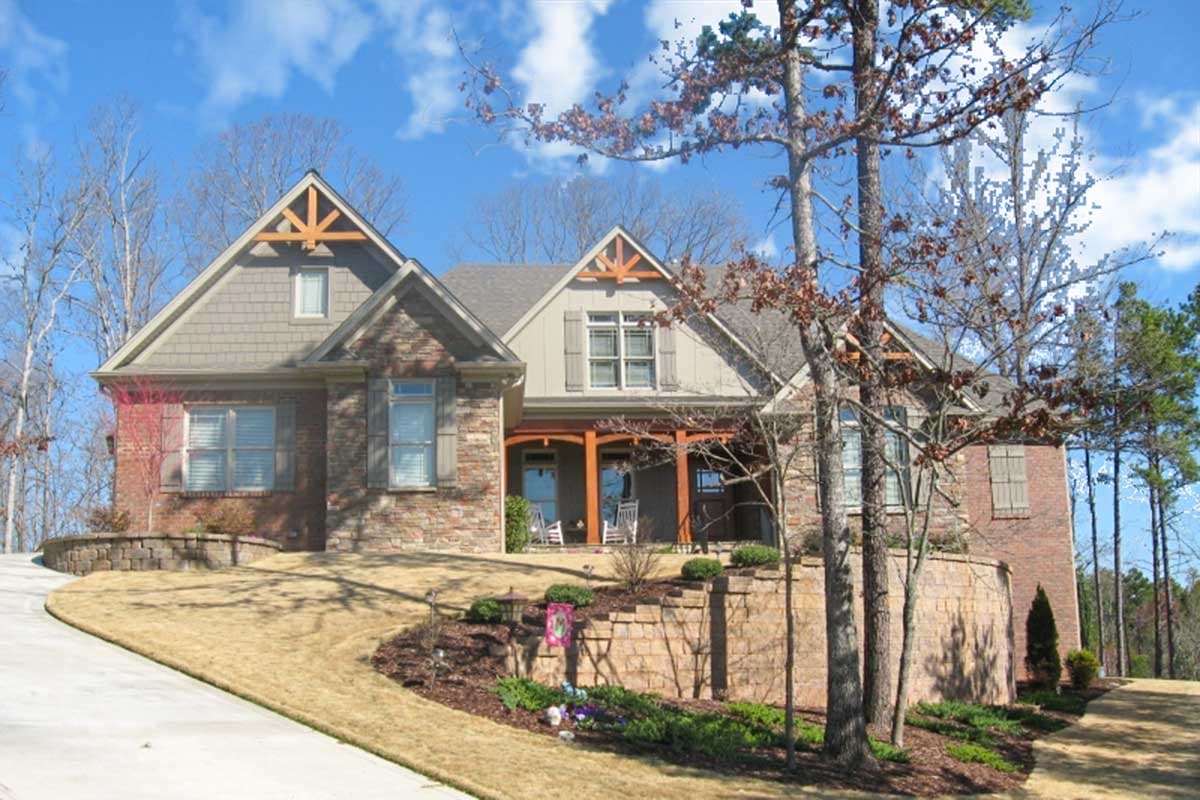 House plan exterior. Craftsman style, one story home. Features include multiple gables, covered porch with columns, and stone and brick facade.