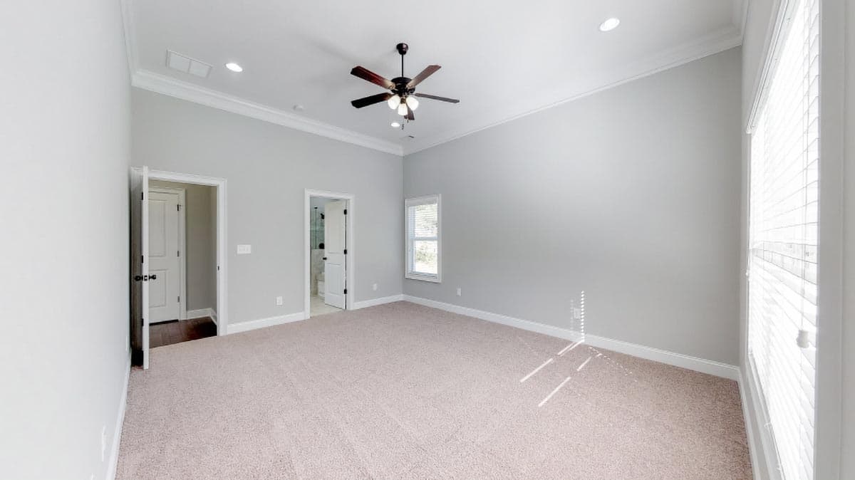 Interior view of a spacious room with a ceiling fan, crown molding, double doors, and a single window.