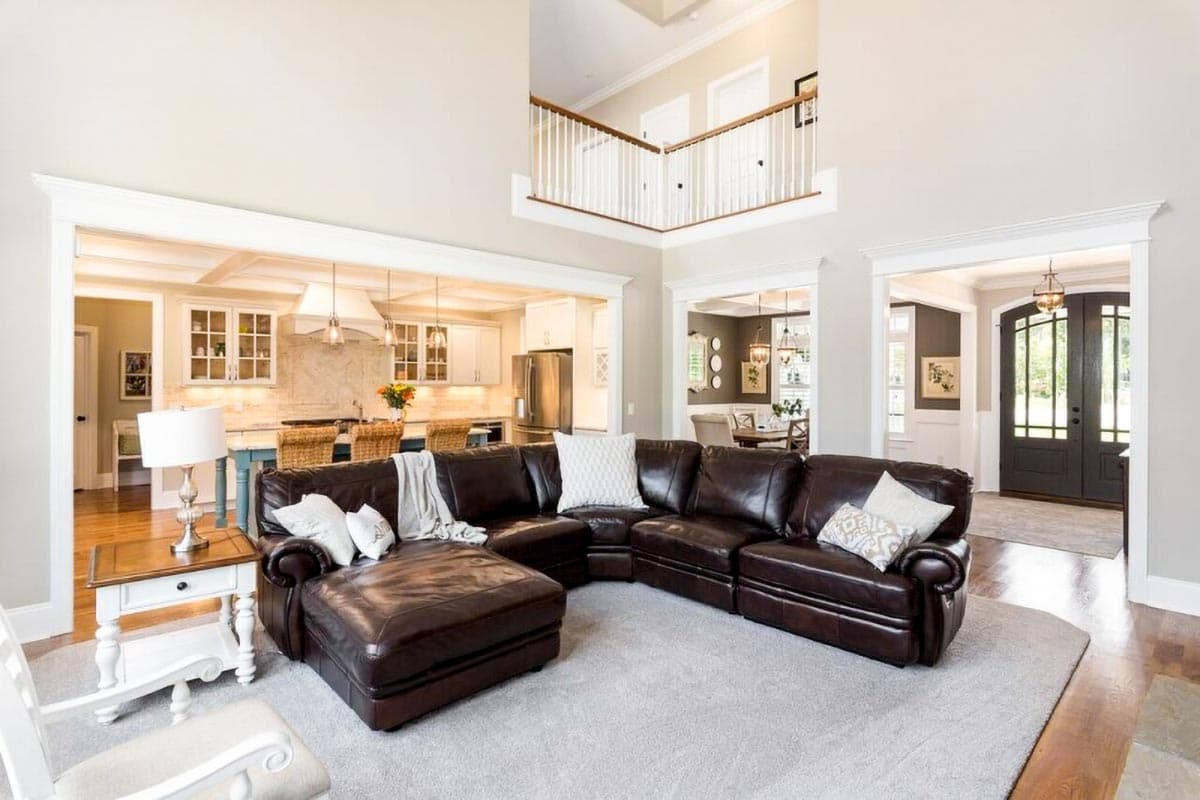 Great room with coffered ceiling, open to kitchen with island and dining area. Two-story foyer with open railing.
