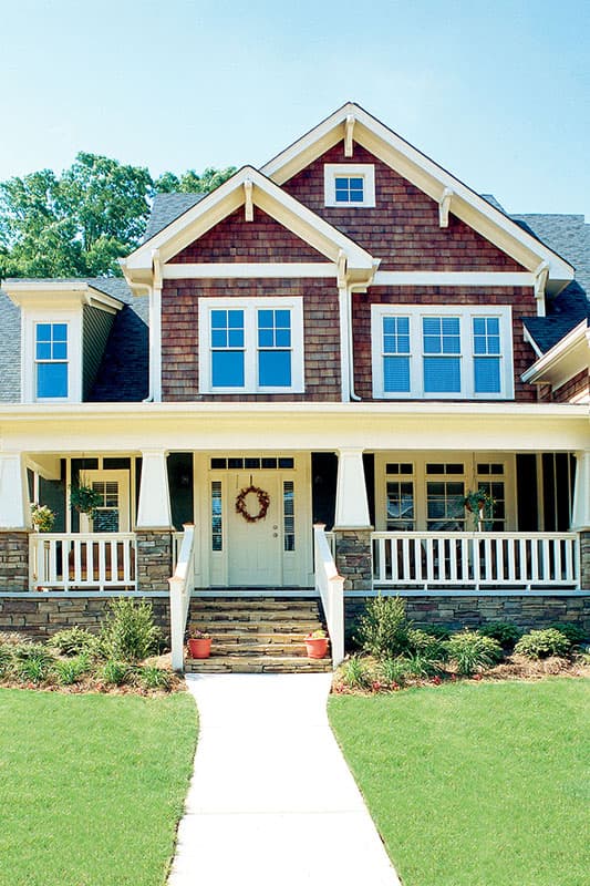 Craftsman style house plan exterior with a wide covered porch, stone accents, multiple gables, and shingle siding.