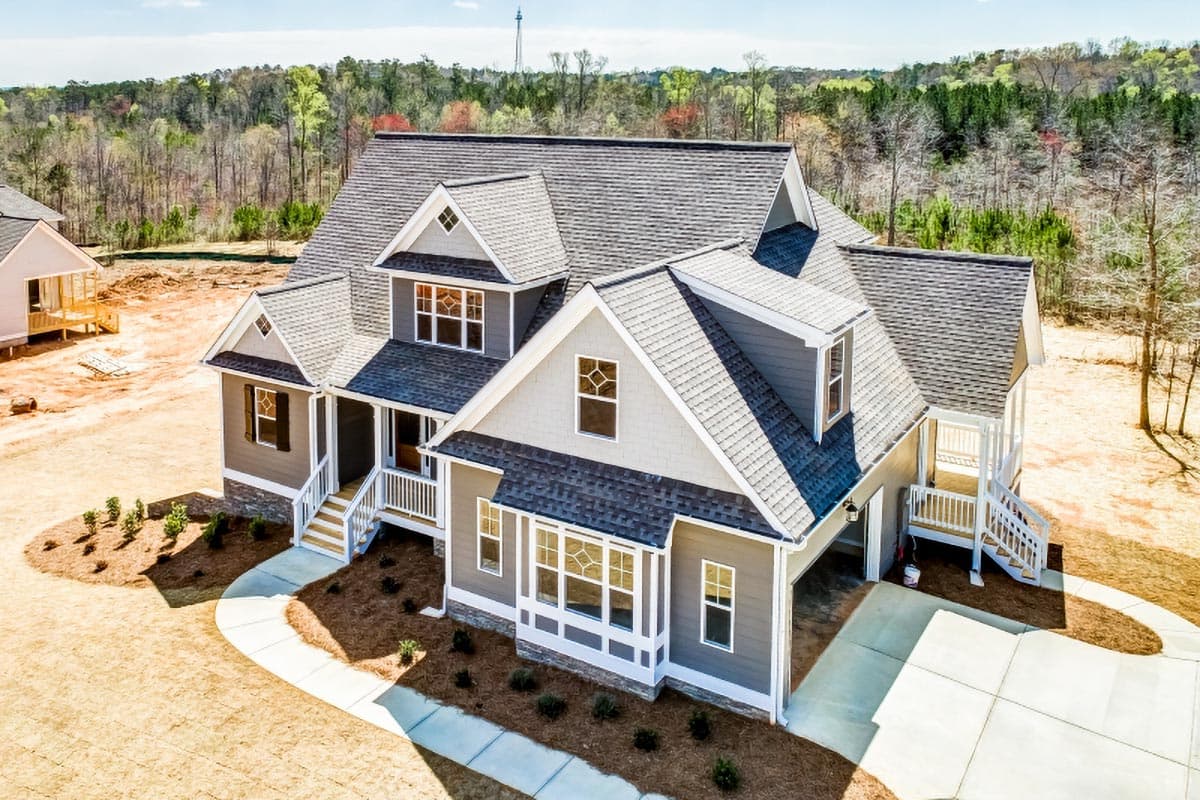 House plan exterior: Two-story home with multiple gables, dormer, covered front porch, and attached garage.
