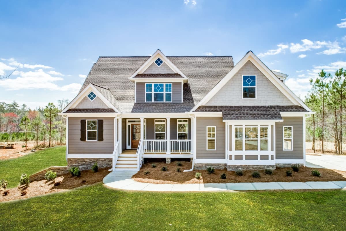 House plan exterior. Two-story home with Craftsman details, a covered front porch, gables, and a bay window. Features a stone skirt.
