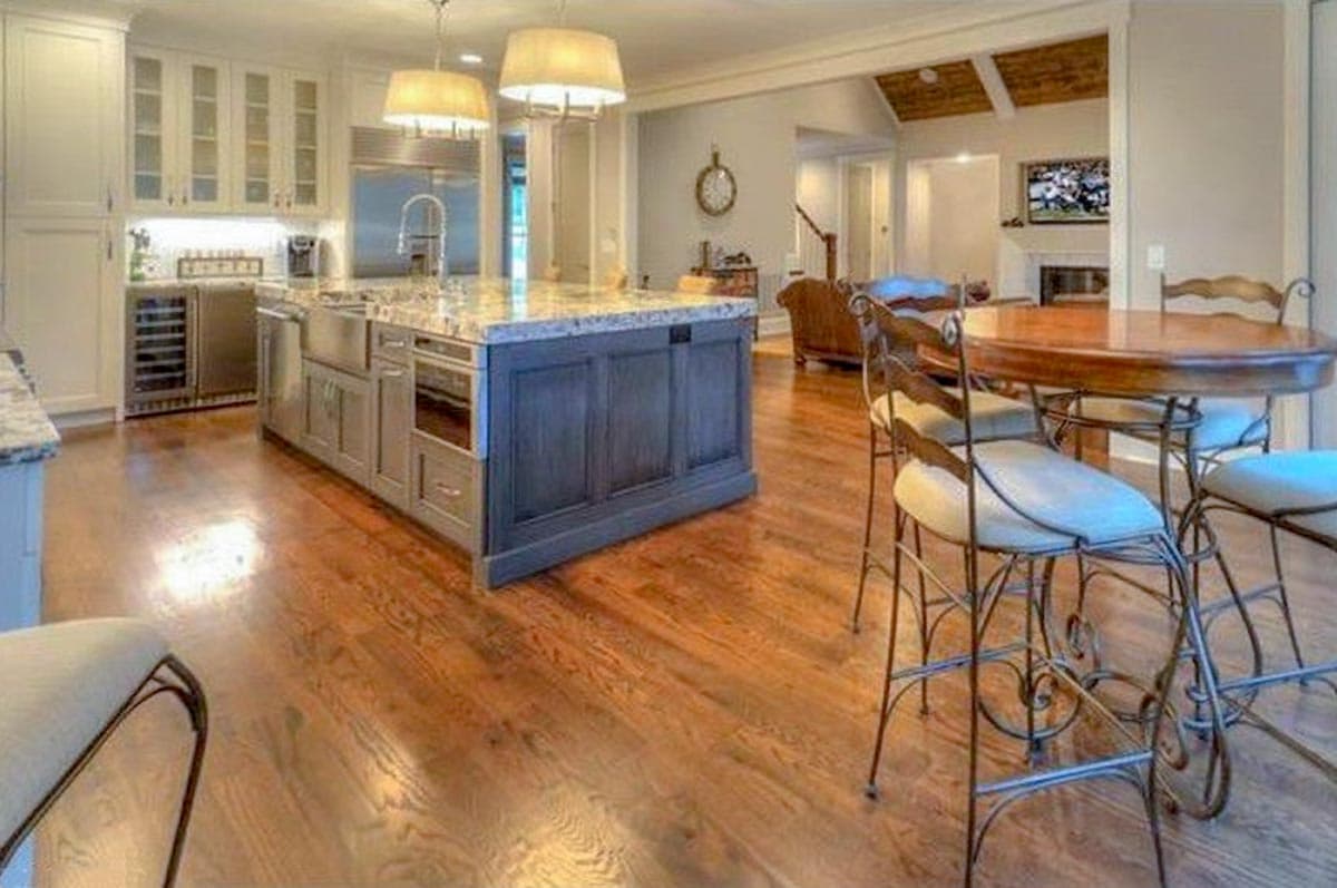 Open concept kitchen and living area with island, counter seating, dining table, and fireplace.
