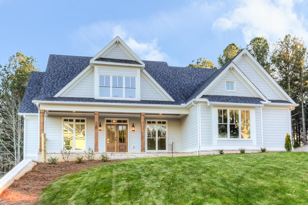 House plan exterior. Two-story home with Craftsman-style elements, front porch supported by columns, gabled roof, and multiple dormers.