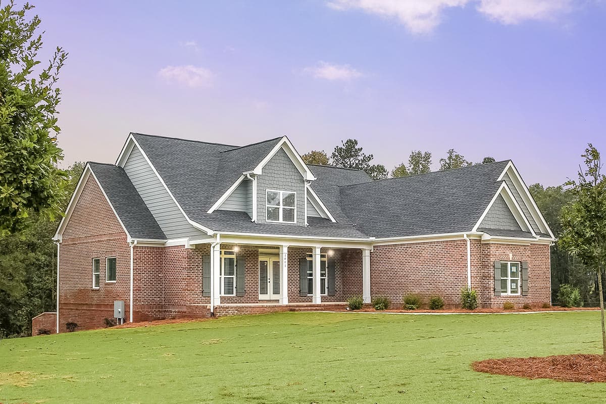 House plan exterior: Ranch style home with brick facade, covered front porch with columns, gabled dormer, and dark asphalt shingle roof.