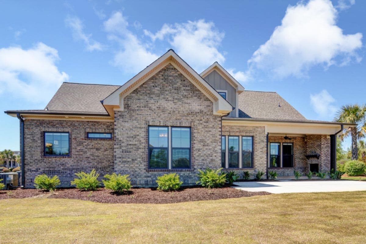 House plan exterior of a one-story brick home with gables, dormers, and a covered porch with fireplace.