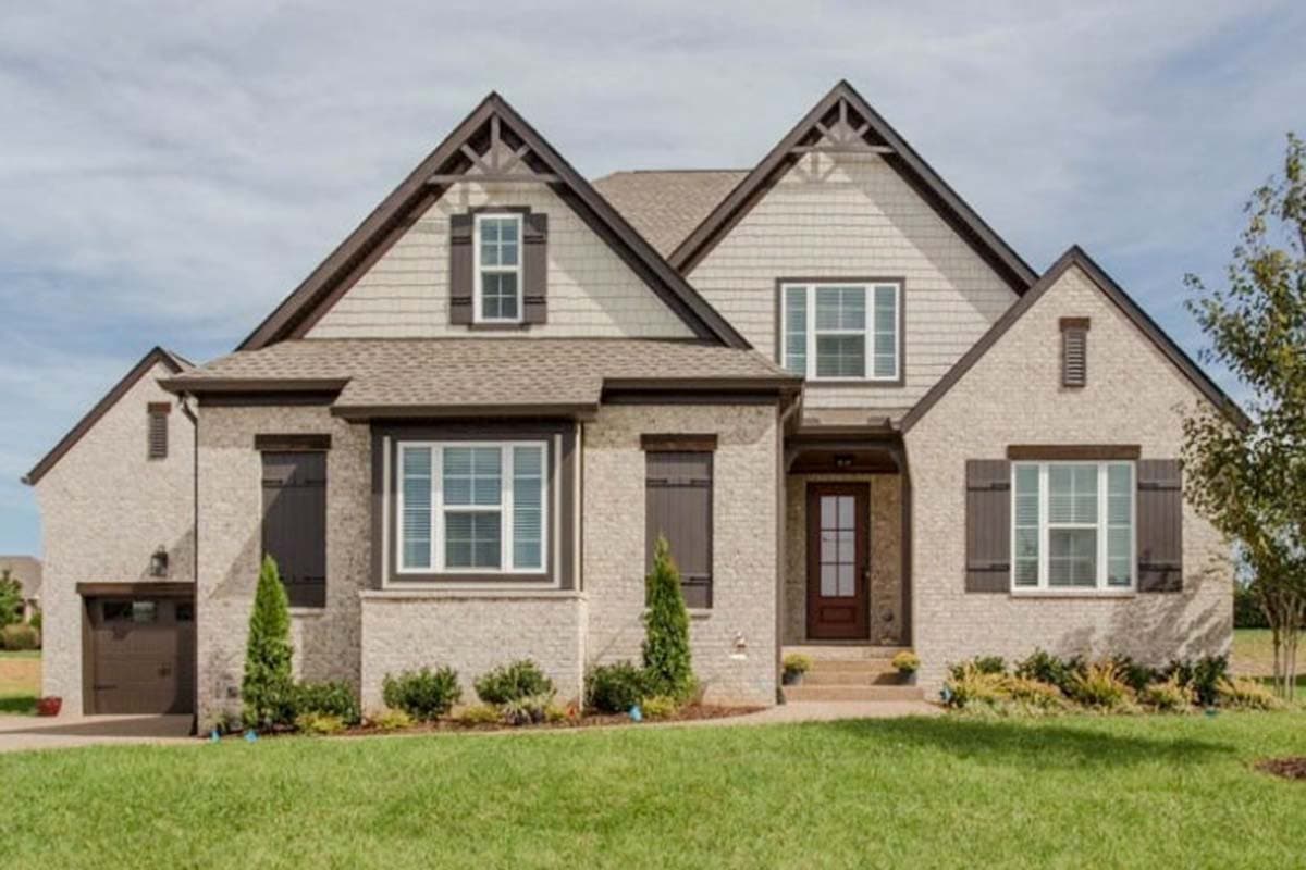 House plan exterior: Two-story Modern Farmhouse with brick facade, prominent gables with decorative brackets, dormers, and side-entry garage.