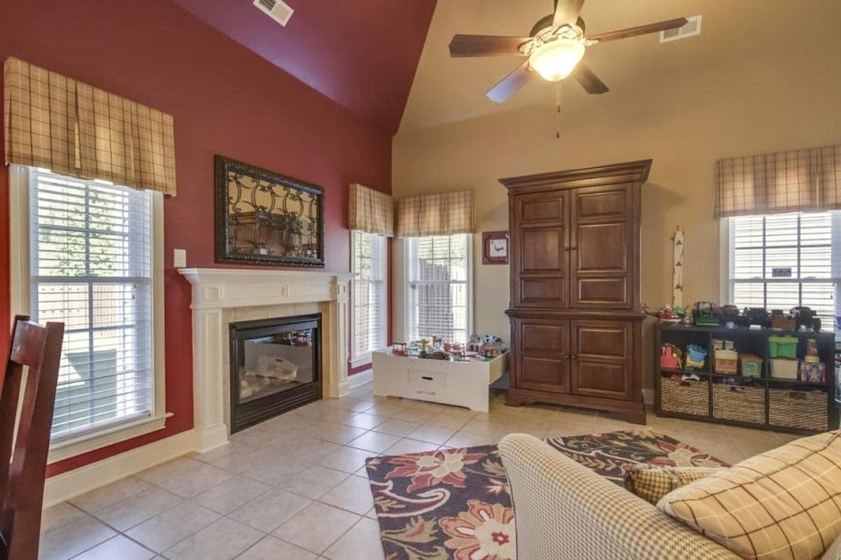 Living room with vaulted ceiling, fireplace, built-in cabinetry, and windows.