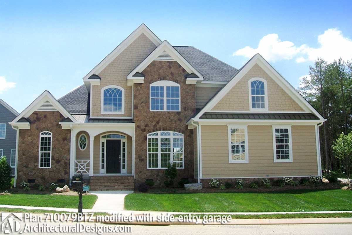 House plan exterior: Two-story home with stone accents, multiple gables, arched and grid windows, and covered entry.