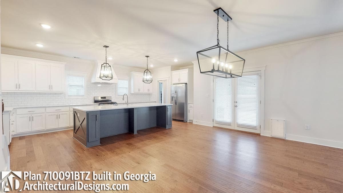 Kitchen featuring a large island with decorative X-braces, white subway tile backsplash, stainless steel appliances, and pendant lighting.