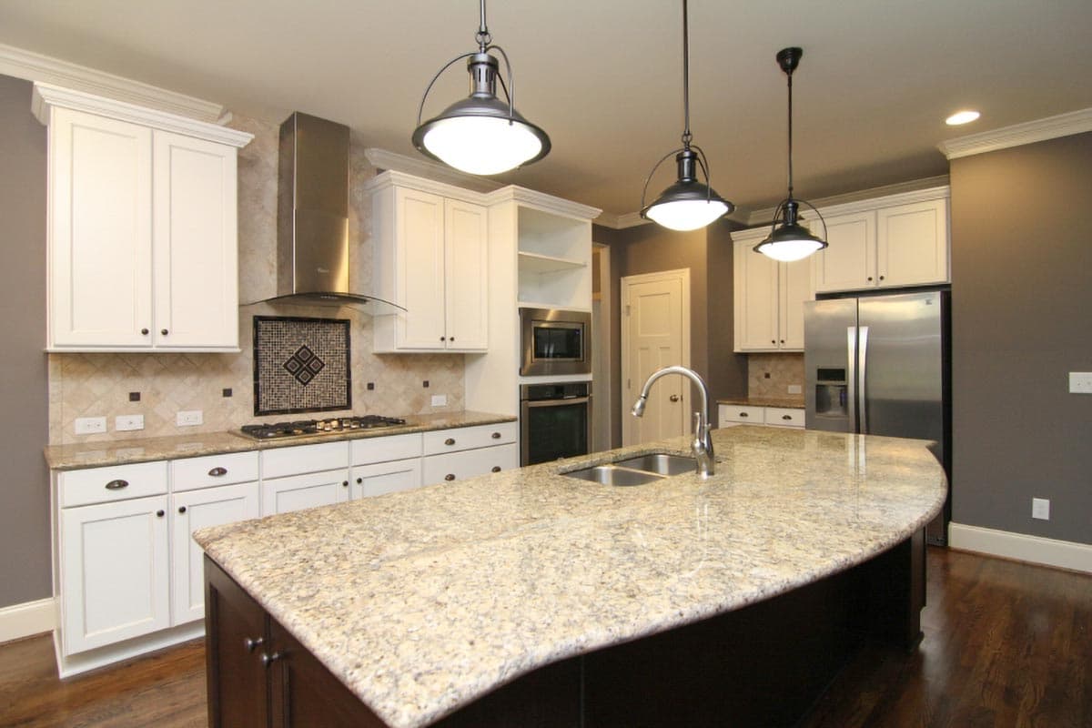 Kitchen with large island featuring a sink, white cabinetry, stainless steel appliances, and pendant lighting.