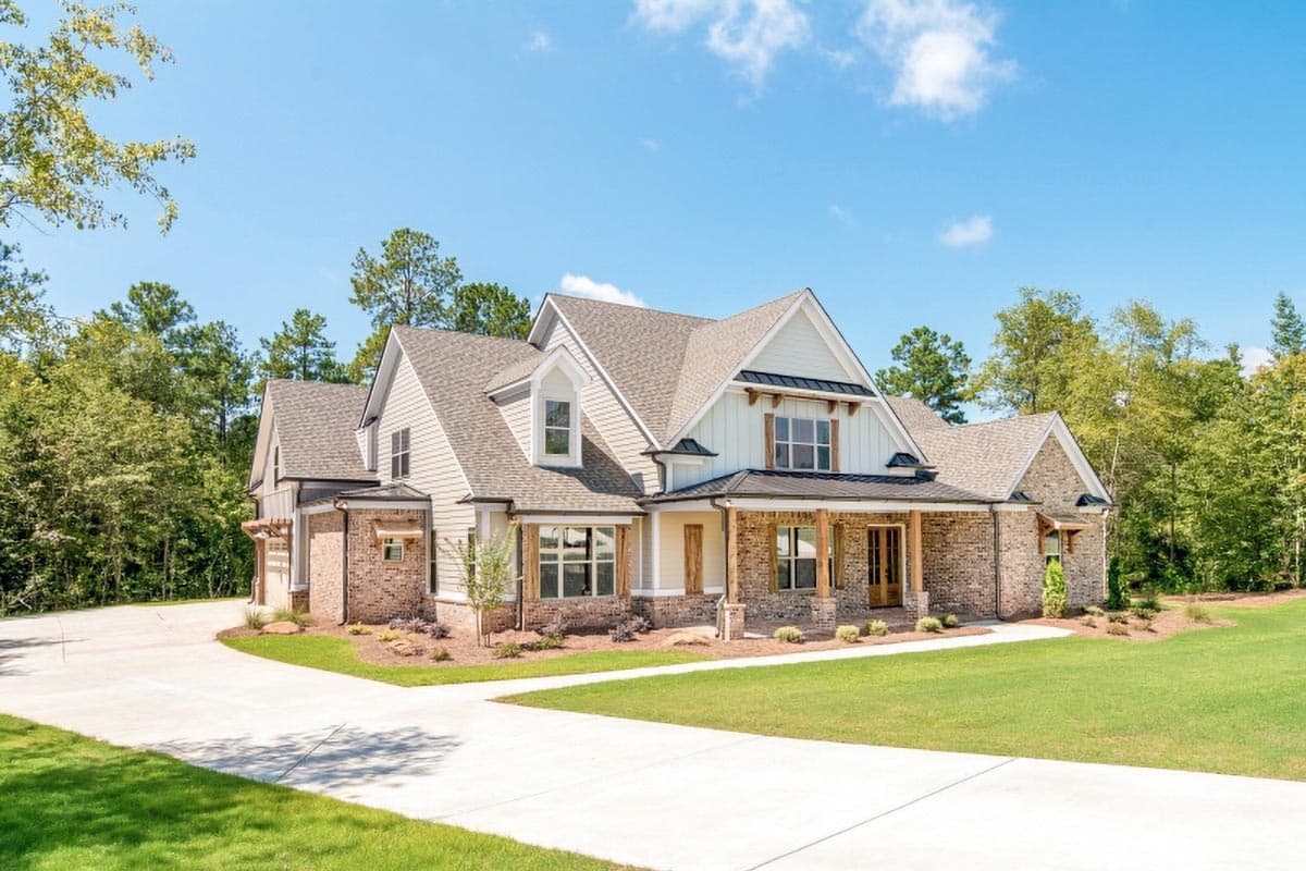 House plan exterior: Modern Farmhouse style, two stories, with a covered front porch, gables, and stone and lap siding.