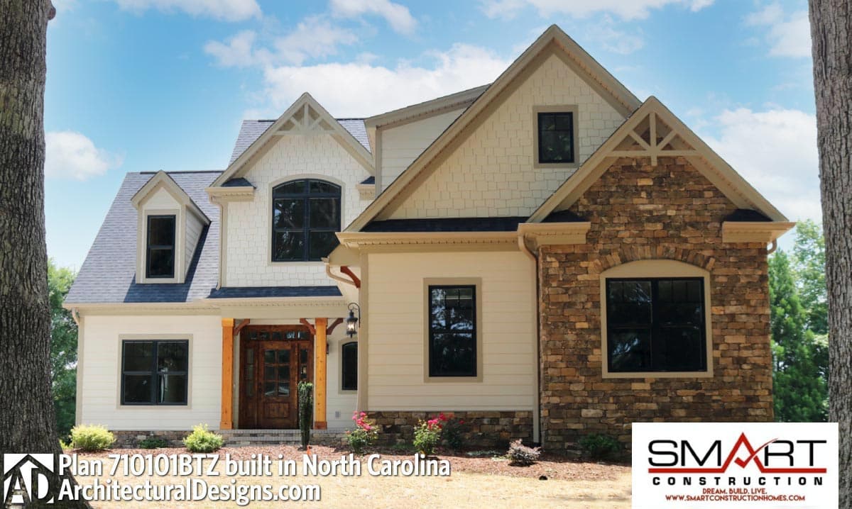 House plan exterior: Two-story home with gables, dormers, stone accents, and wood-trimmed entrance.