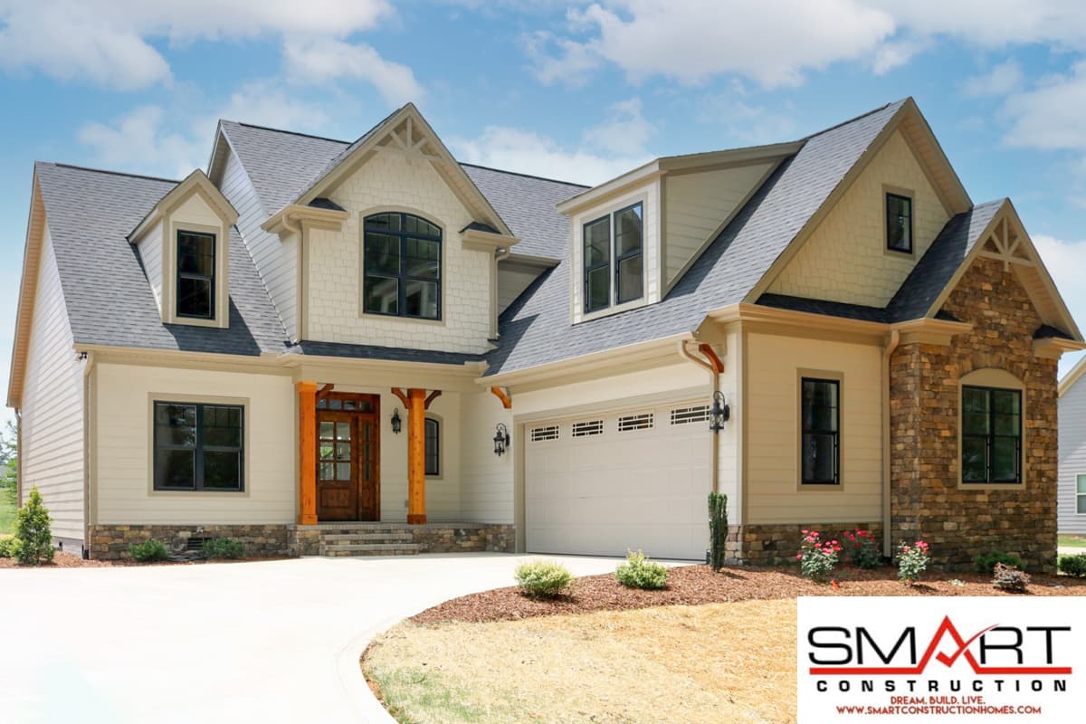 House plan exterior: Two-story home with gabled dormers, stone accents, wooden porch posts, and a side-entry garage.
