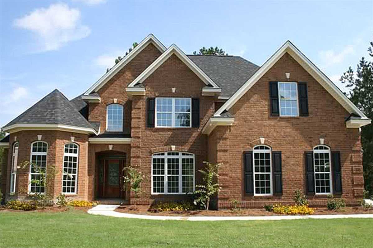House plan exterior: Two-story brick home with multiple gables, arched windows, and a prominent circular turret.
