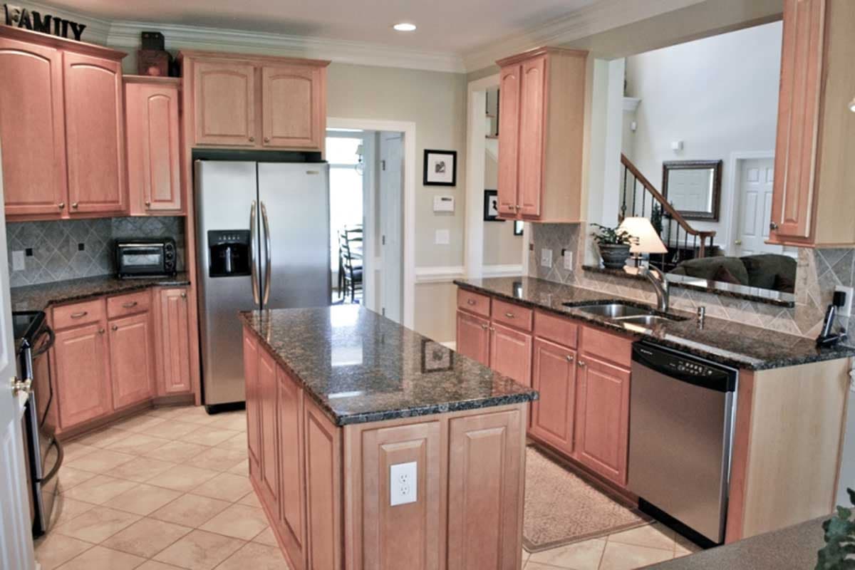 Kitchen interior with wood cabinets, granite countertops, stainless steel appliances, and central island.