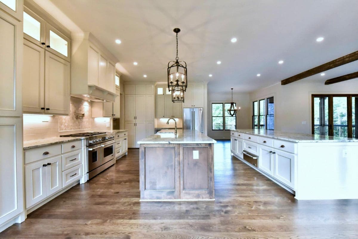 Open concept kitchen with dual islands, a gas range, custom cabinetry, and pendant lighting.
