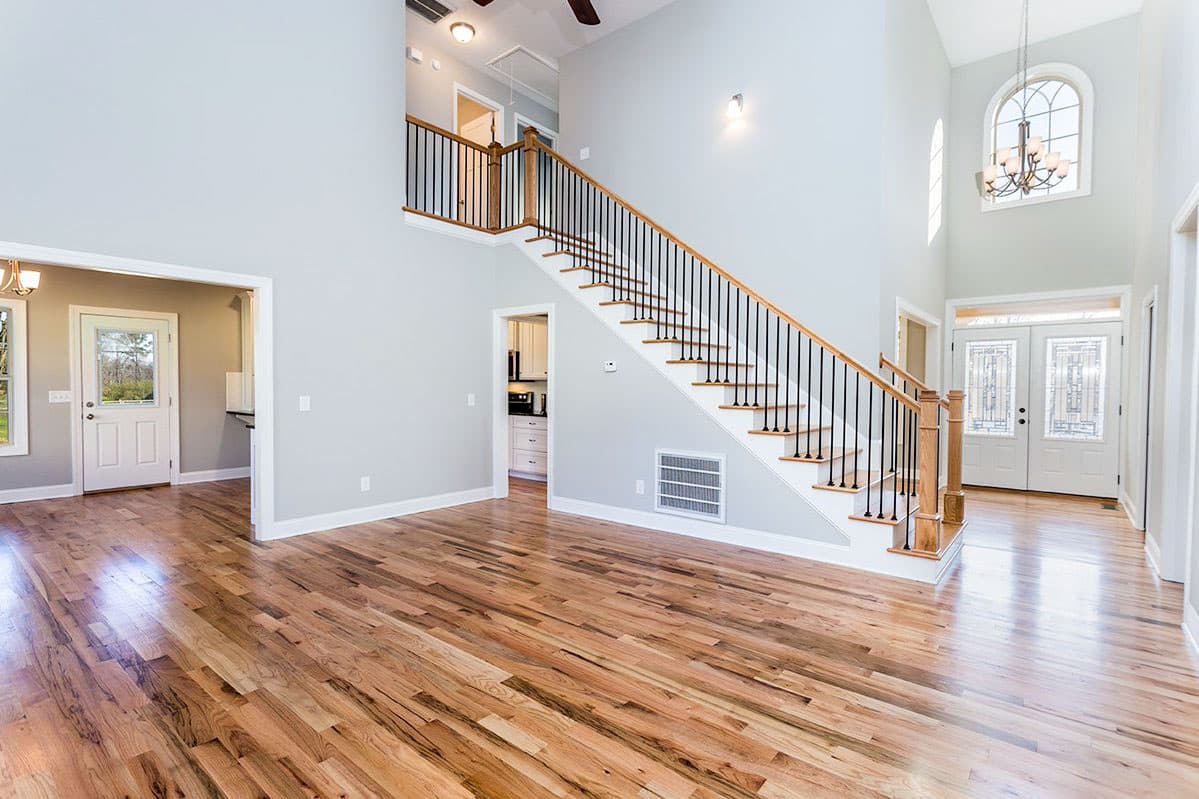 Interior view of a house plan showing a two-story foyer with a staircase, double entry doors, and an arched window.