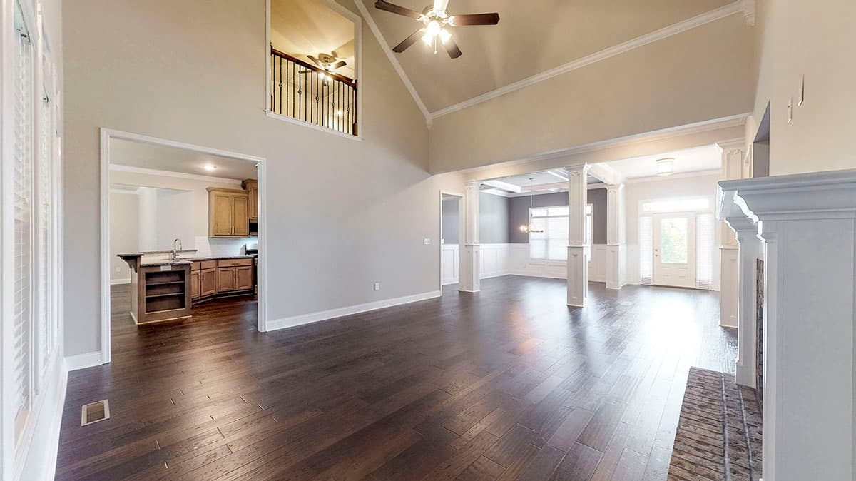 Interior view of open concept great room with vaulted ceiling, fireplace, view of kitchen, and second story overlook.