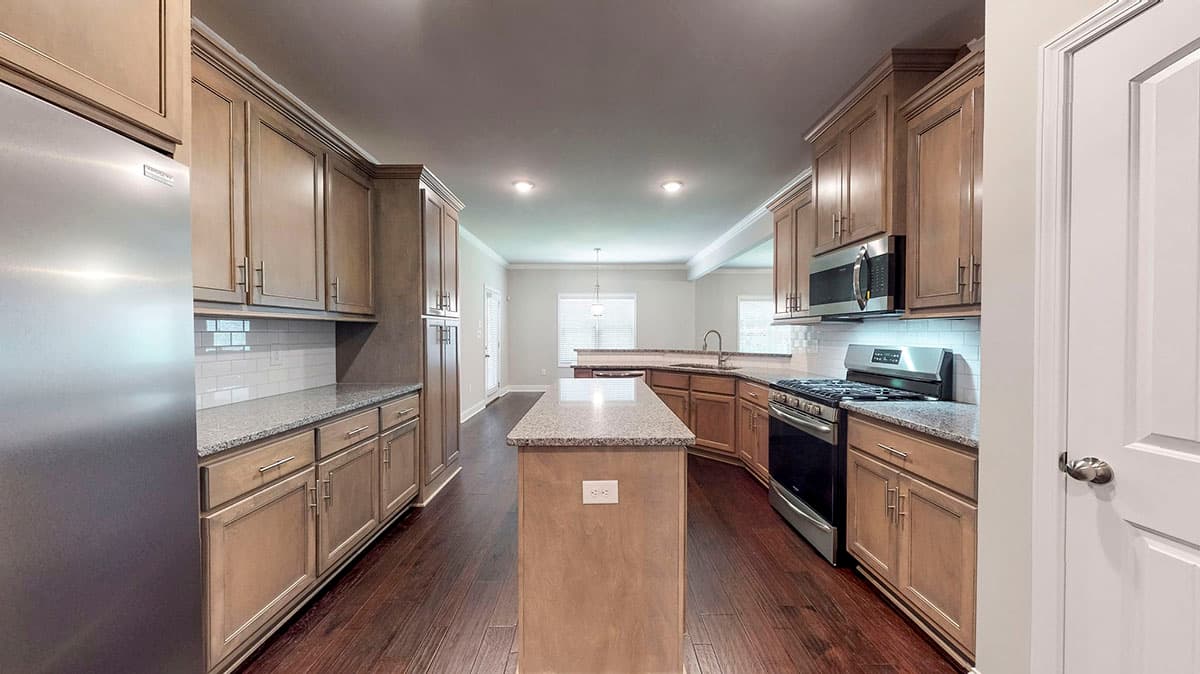 Kitchen with island, granite countertops, subway tile backsplash, stainless steel appliances, and light wood cabinetry.