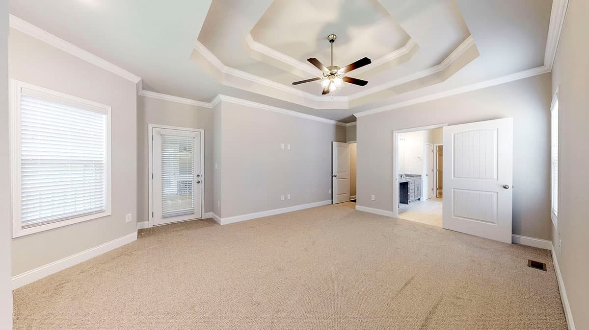 Spacious room with a coffered ceiling, fan, window, door to exterior, and entry to bathroom.