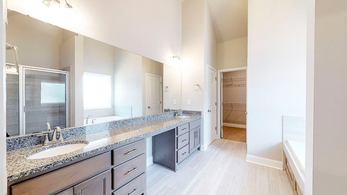 Spacious bathroom with dual vanity, glass-enclosed shower, soaking tub, and walk-in closet.
