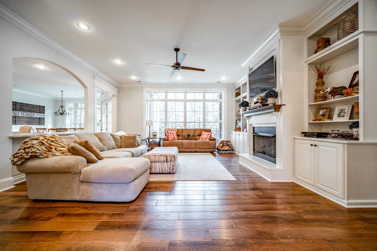 Interior view of a great room with sectional sofa, fireplace with built-in shelving, and large window wall.