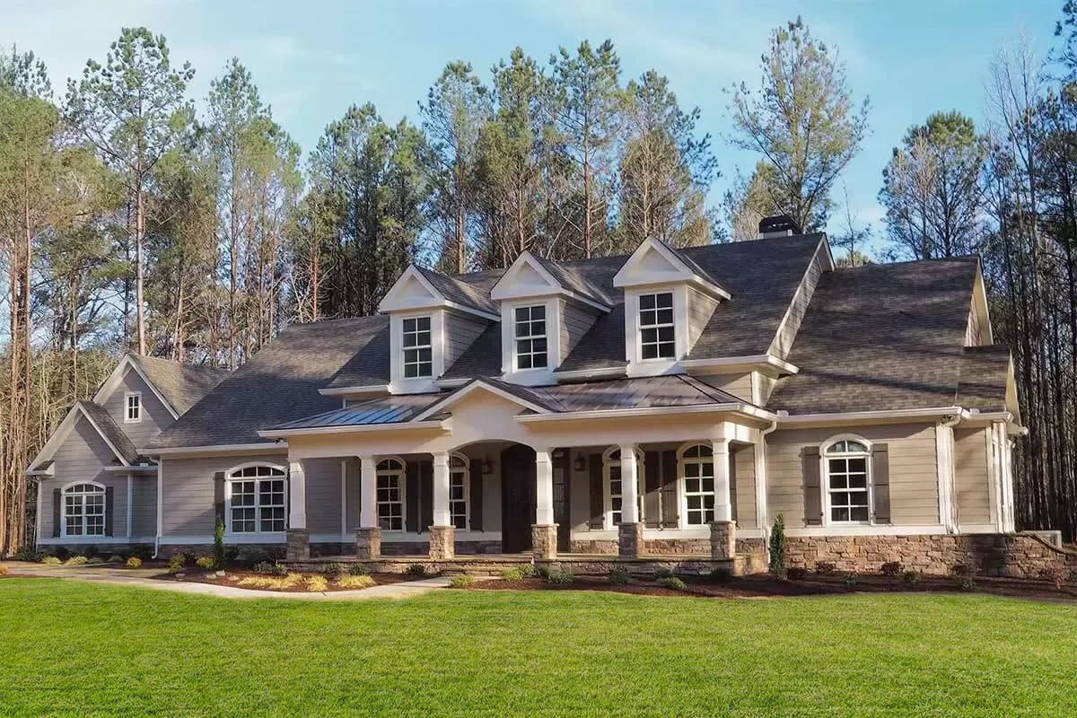 House plan exterior. Two-story with front porch, multiple dormers, and a gable roof. Features include stone accents and large windows.