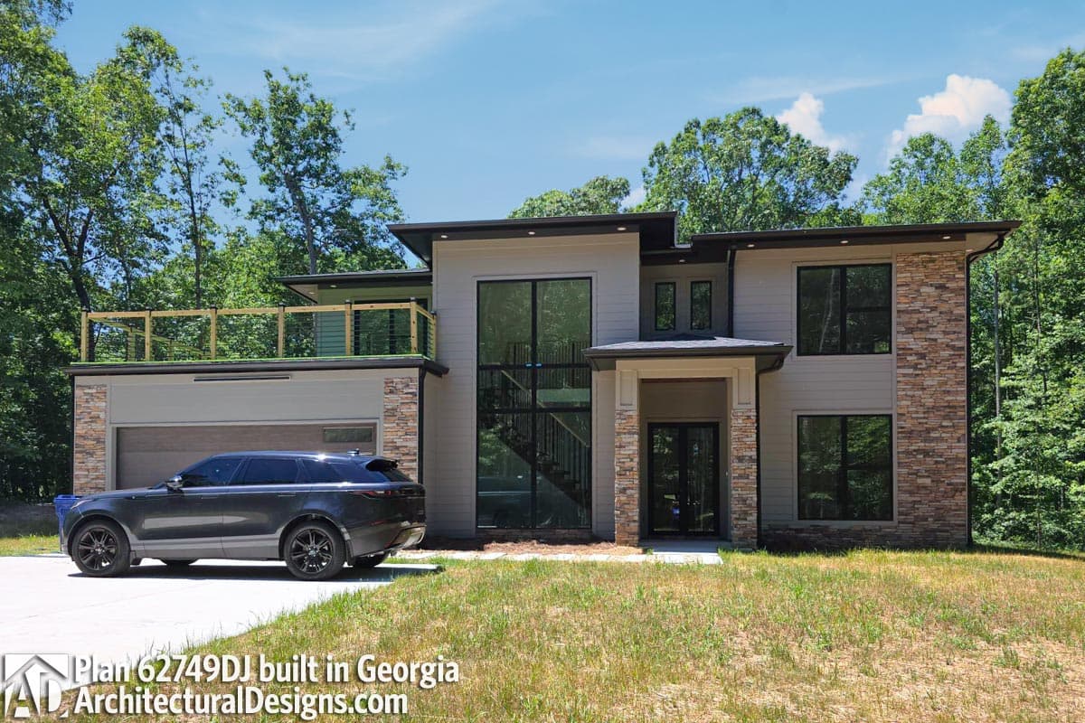 Modern house plan exterior with stone accents, second-story balcony, large windows, and a side-entry garage.