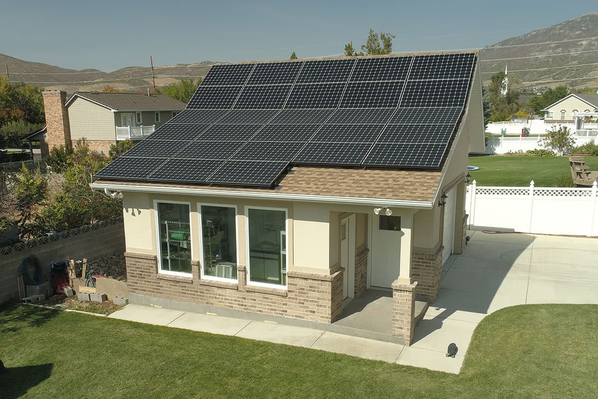 Exterior house plan with attached garage, covered porch, and large roof-mounted solar array.