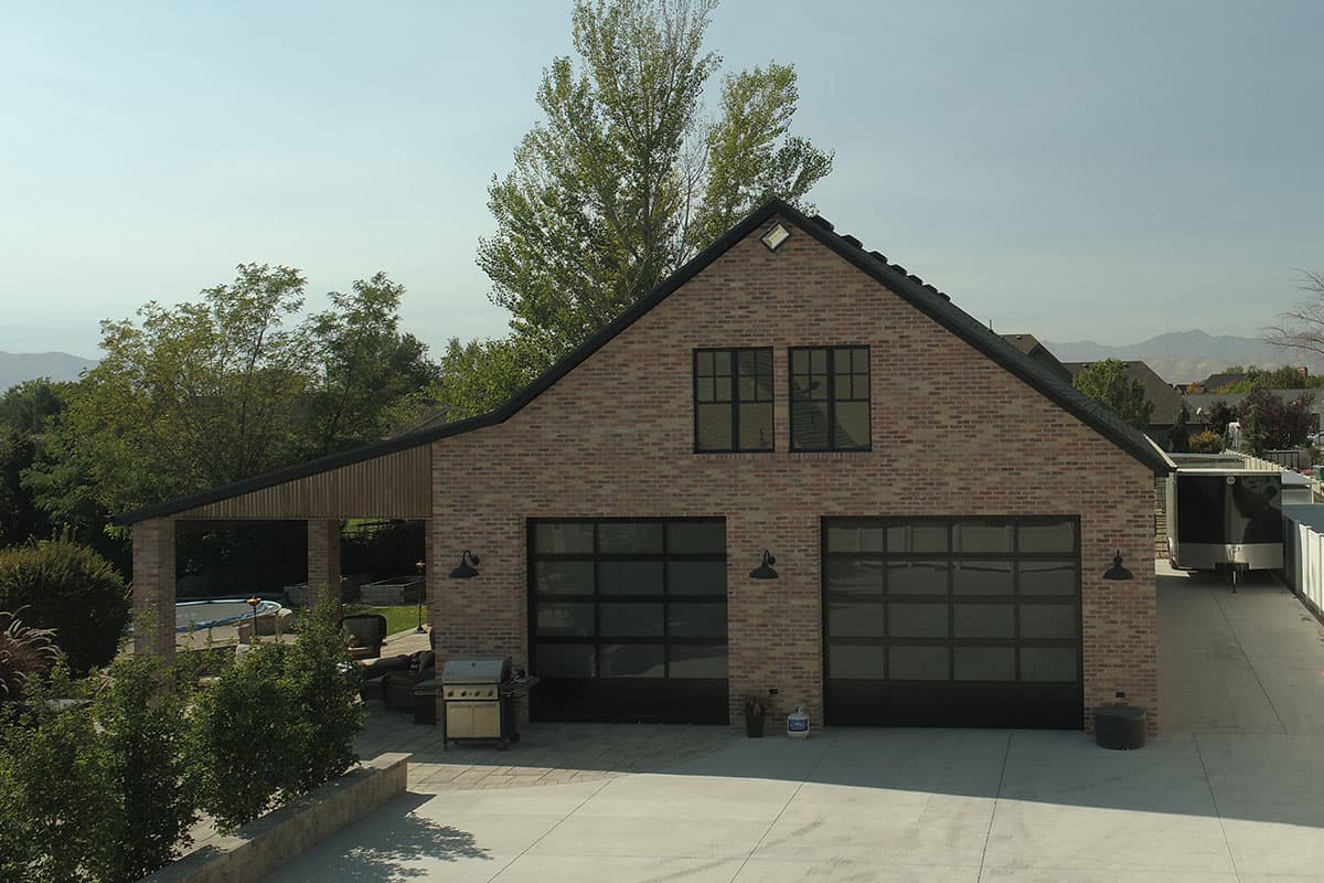 House plan exterior with brick facade, two-car garage with glass doors, and covered patio.