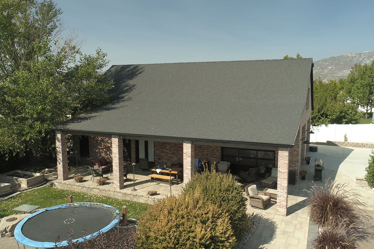 House plan exterior with brick siding, deep covered patio, and gabled roof.