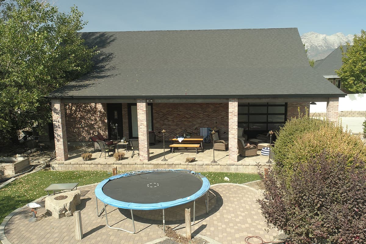 House plan exterior with covered porch, brick facade, and modern garage door.