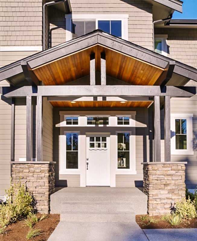House plan exterior with stone-clad columns supporting a gabled roof over the entry. Features shingle siding.