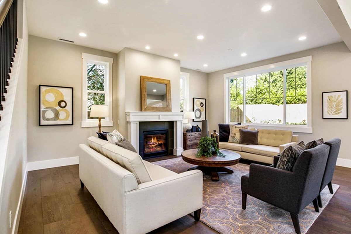 Interior rendering of a living room with fireplace, seating, and large windows.
