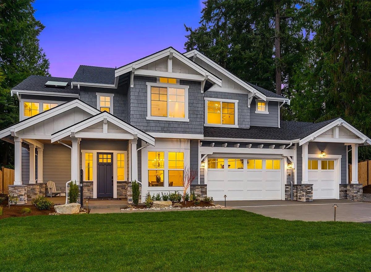 House plan exterior. Two-story Craftsman home with a gabled roof, covered porch with columns, and attached two-car garage.