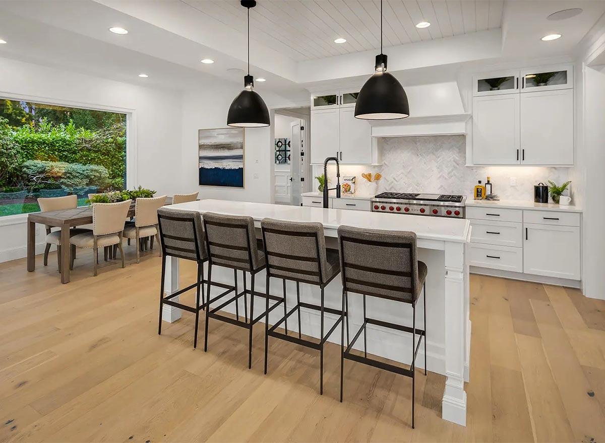 Open concept kitchen and dining area with a large island, bar seating, and dining table near a wide window.