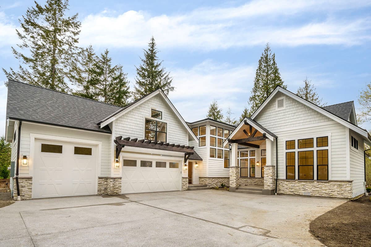 House plan exterior. Modern farmhouse style with gabled roof, two-car garage, stone accents, and covered entry porch.
