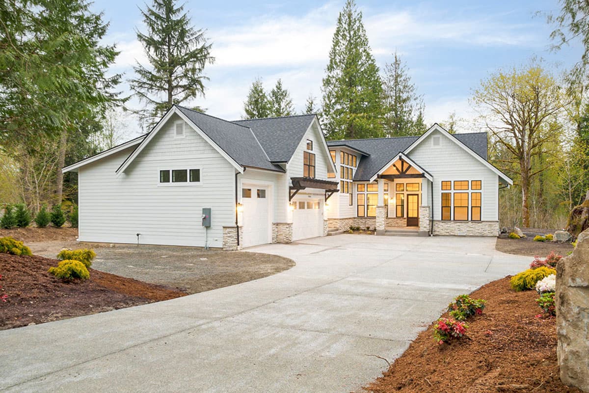 Modern Farmhouse style house plan exterior with a 2-car garage, gables, stone accents, and large windows.
