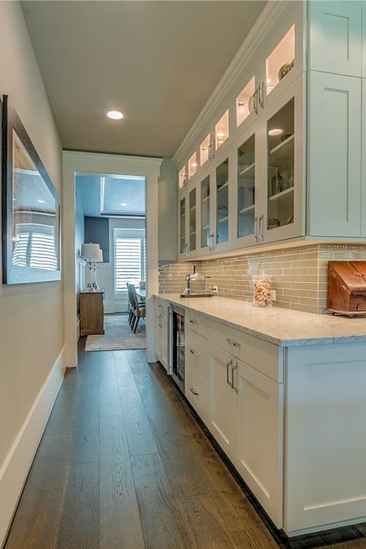Butler's pantry with white cabinetry, glass-front upper cabinets, granite countertop, and wine fridge.