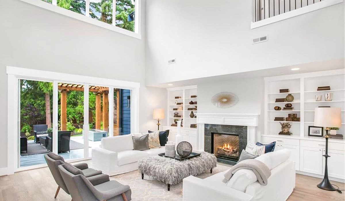 Great room with vaulted ceiling, fireplace, built-in bookshelves, and sliding glass doors to an outdoor patio.