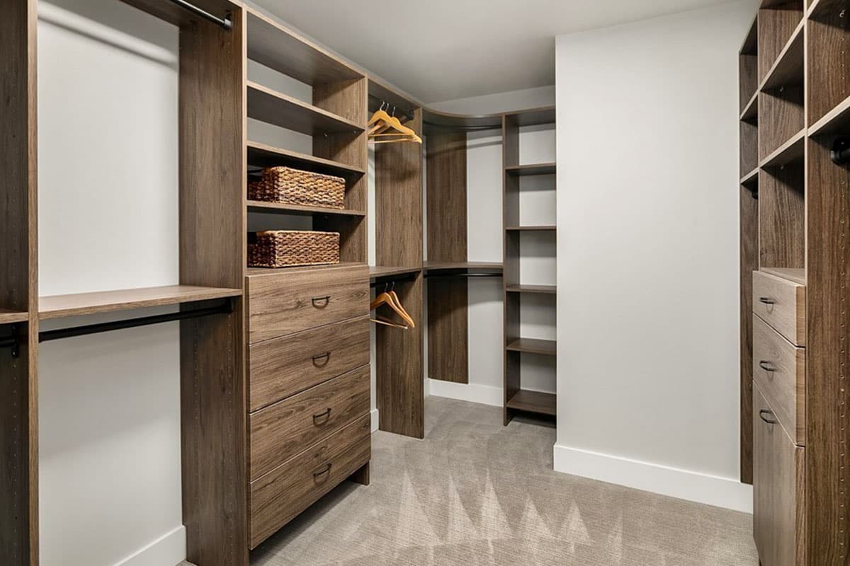 Walk-in closet with built-in wood-finish shelving, drawers, and hanging rods.