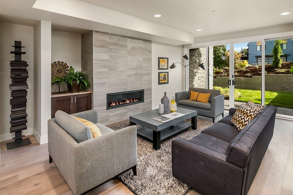 Living room featuring a linear gas fireplace with tile surround, contemporary seating, and large sliding glass doors opening to a backyard.