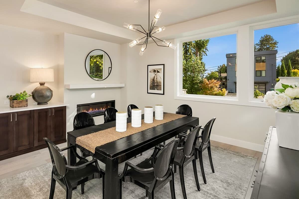 Dining room with fireplace, large windows, modern chandelier, and dark wood buffet.