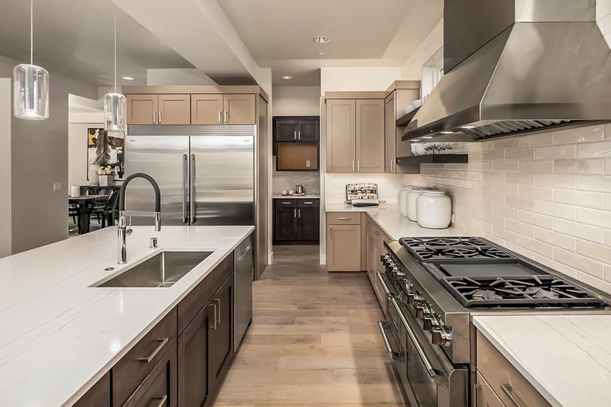 Contemporary kitchen with large island sink, stainless steel appliances, gas range, and white subway tile backsplash.