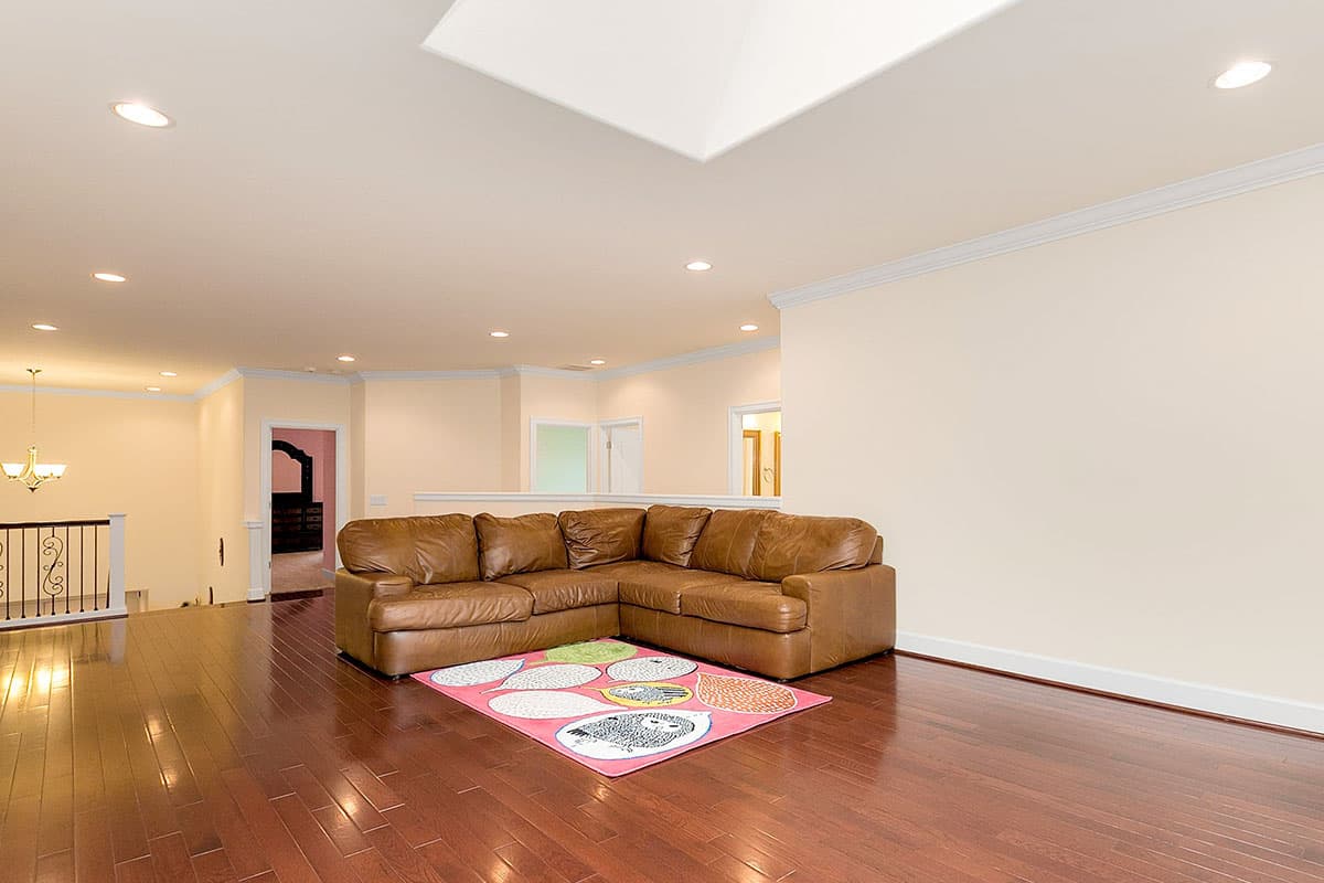 Interior view of living area with sectional sofa, area rug, recessed lighting, skylight, and hardwood floors.