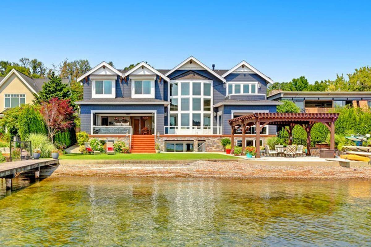 Modern house plan exterior with multiple gables, a prominent central window wall, and a lakefront pergola.