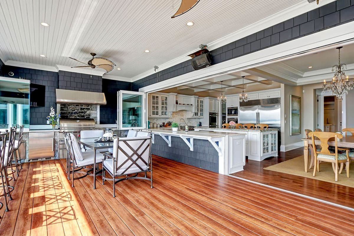 Open concept kitchen and dining area with large island, built-in grill, and adjacent seating.