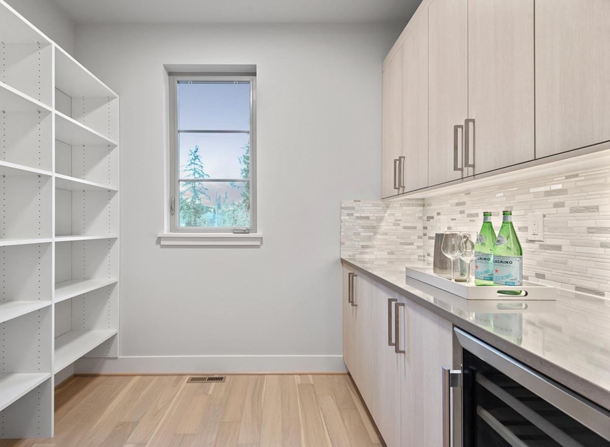 Pantry with wall shelves, counter, cabinets, wine fridge, and window.