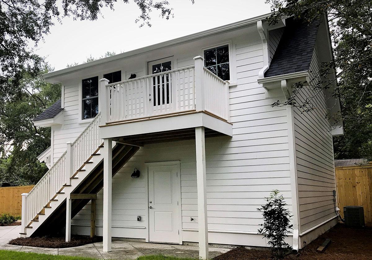 House plan exterior: Two-story modern farmhouse with white siding, front-facing gable, and elevated deck with stairs.